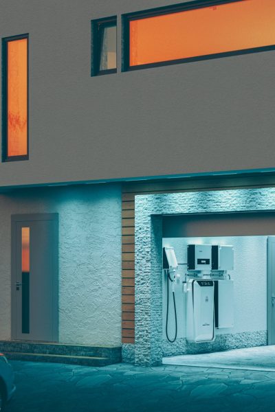 concept of a home battery energy storage system located in the garage of a modern family house in a futuristic blue light illuminating the evening atmosphere of a quiet street. 3d rendering.
